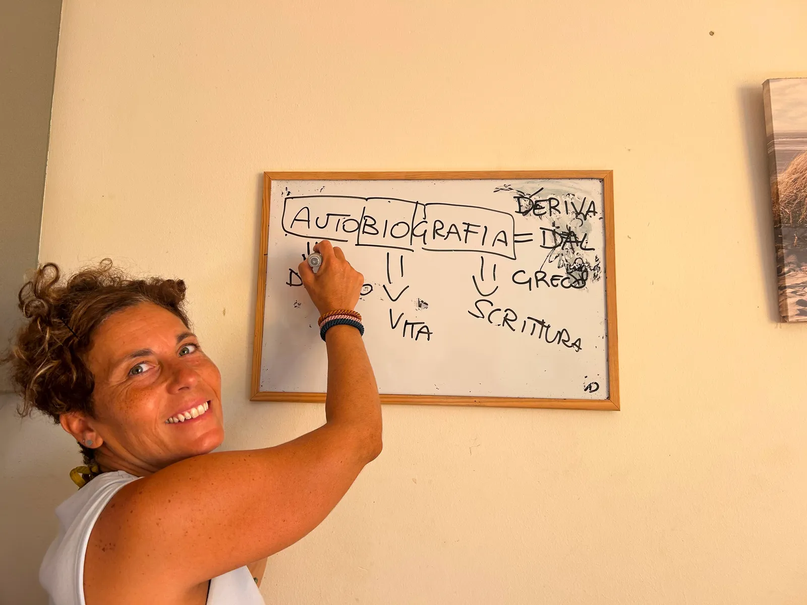 Nadia sonríe mientras escribe un esquema sobre la autobiografía en una pizarra