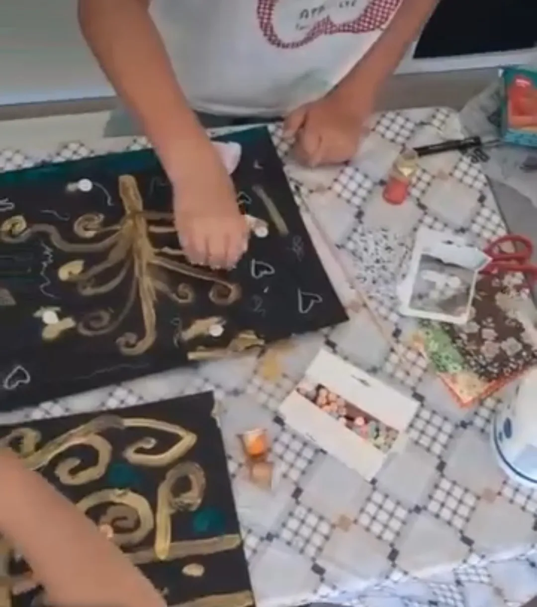 Manos de un niño pintando con dorados un lienzo negro al estilo de Klimt