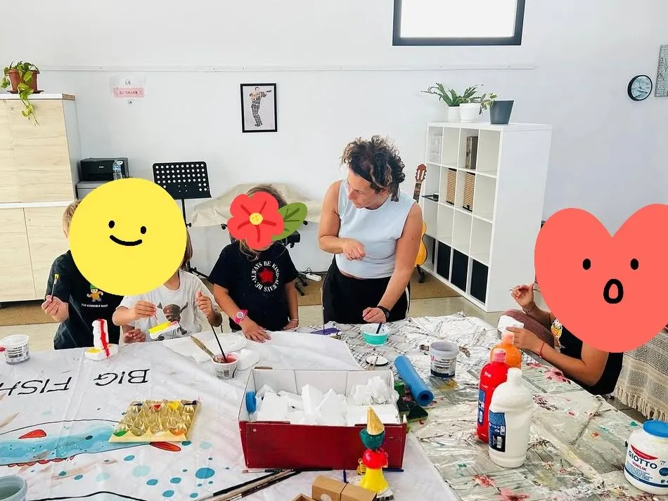 Nadia dirige un taller de pintura con niños alrededor de una mesa llena de materiales