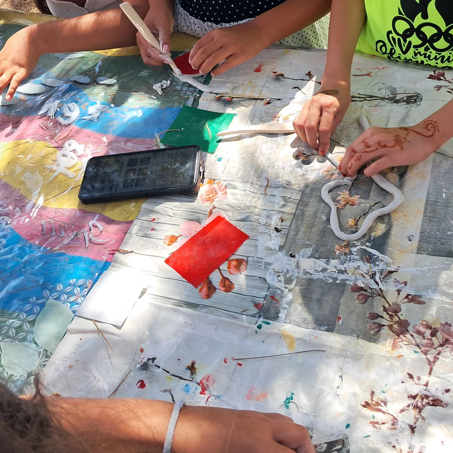 Manos trabajando con pintura sobre un lienzo colectivo en el taller